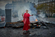 Place d'Italie encore, une femme vêtue comme la Justice, un glaive à la main et un écriteau dans l'autre disant <em>"Et pendant que des gens brûlent… Ils se baignent dans le champagne!!"</em>, trônait cet après-midi près d'un amoncellements de gravas encore fumants. ©Kiran Ridley/Getty Images