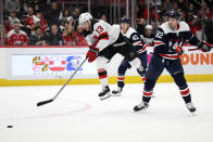 New Jersey Devils center Nico Hischier (13) leaps after the puck against Washington Capitals center Evgeny Kuznetsov (92) and defenseman Martin Fehervary (42) during the second period of an NHL hockey game, Saturday, March 26, 2022, in Washington. (AP Photo/Nick Wass)