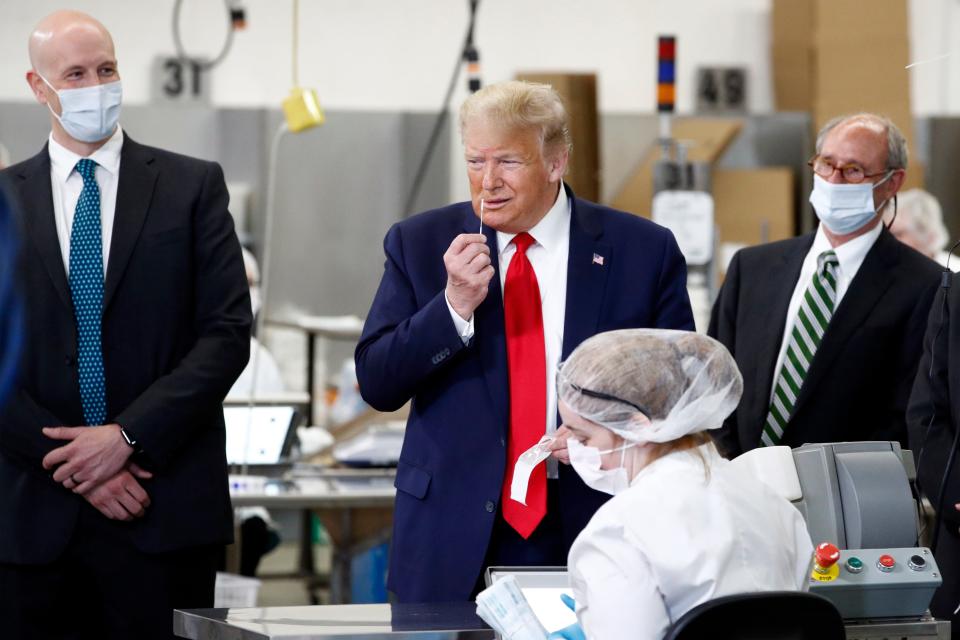 President Donald Trump holds a medical swab near his nose as he tours Puritan Medical Products, a medical swab manufacturer, on Friday in Guilford, Maine.