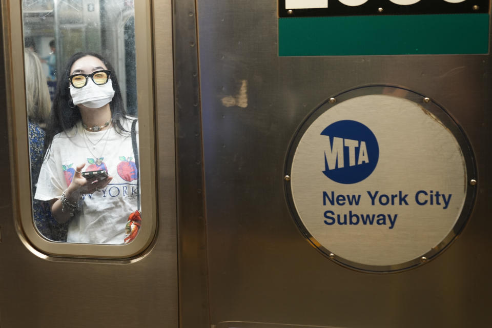 Commuters, one wearing a mask, ride the subway in New York, Friday, June 14, 2024. New York Gov. Kathy Hochul says she is considering a ban on face masks in the New York City subway system, following what she described as concerns over people shielding their identities while committing antisemitic acts. (AP Photo/Seth Wenig)