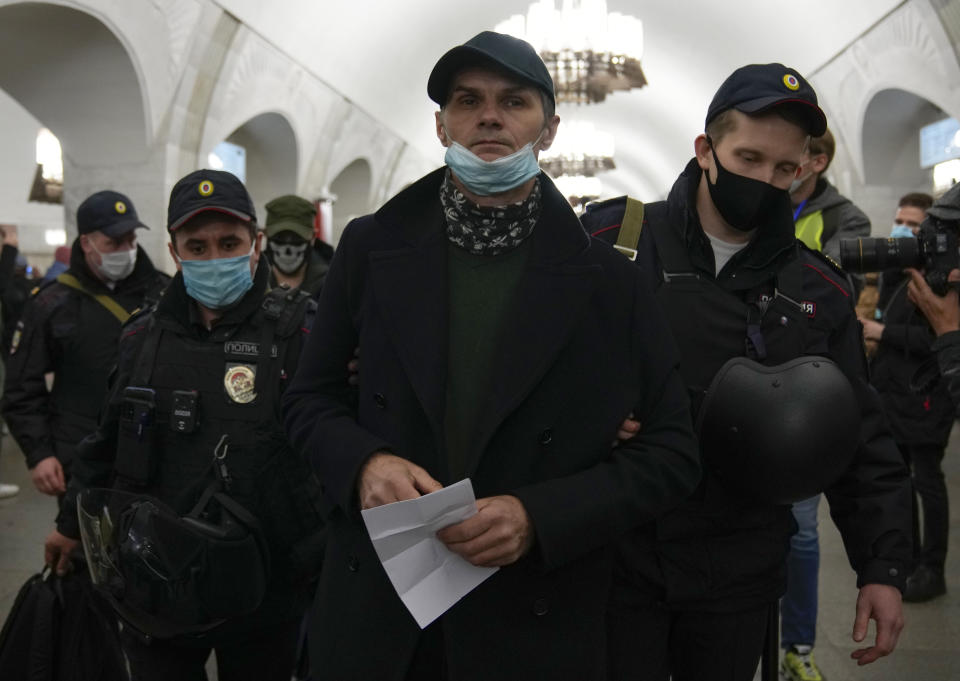 Police officers wearing face masks to help curb the spread of the coronavirus detain a protestor during an unsanctioned action to mark National Unity Day in Moscow, Russia, Thursday, Nov. 4, 2021. The Moscow authorities banned their traditional "Russian March" in Moscow celebrating People's Unity Day due to the COVID-19 pandemic. (AP Photo/Alexander Zemlianichenko)