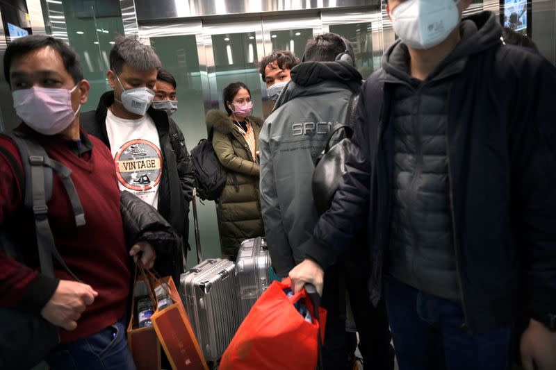 People arriving at the Beijing Daxing International Airport wear protective face masks in an elevator of a subway station, as the country is hit by an outbreak of the novel coronavirus, in Beijing