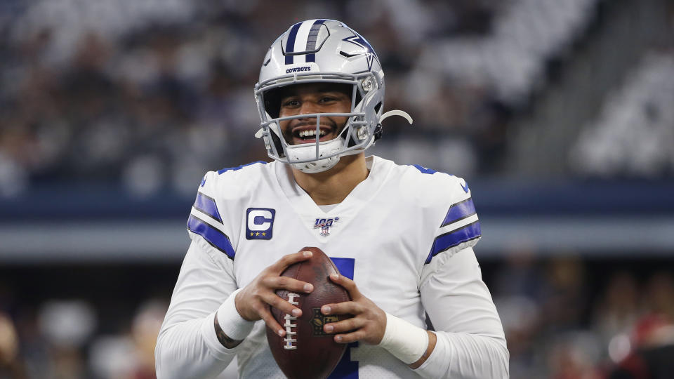 Dak Prescott smiles while holding a football. 