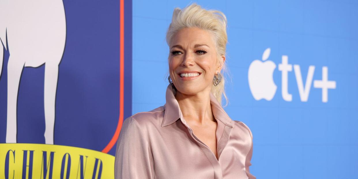 hannah waddingham smiling and wearing a light mauve silk shirt posing on the red carpet