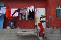 El payaso de circo Julio Cesar Chiroque, de 38 años, cuyo nombre de payaso es "Galleta", sale de una residencia donde no vendió manzanas confitadas mientras circula en un barrio pobre en las afueras de Lima, Perú, el miércoles 20 de agosto de 2020. (AP Foto/Martín Mejía)