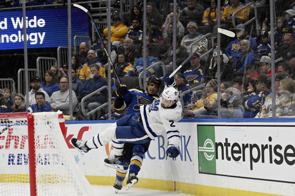 Toronto Maple Leafs' Simon Benoit (2) is checked by St. Louis Blues' Brayden Schenn (10) during the second period of a hockey game on Monday, February 19, 2024, in St. Louis. (AP Photo/Michael Thomas)