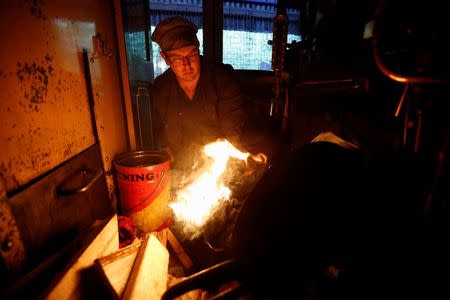 Puffing Billy trainee fireman Winston Martin lights a fire to put into the firebox of a steam locomotive, part of the four-hour-long process to prepare the engine, at Belgrave near Melbourne, October 20, 2014. REUTERS/Jason Reed