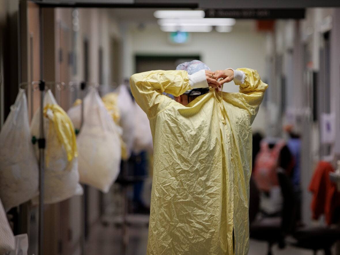 A nurse gowns up before attending to a patient in the intensive care unit of Humber River Hospital, in Toronto, on Jan. 25, 2022. (Evan Mitsui/CBC - image credit)