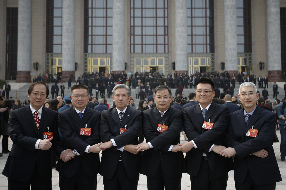 Delegates pose for a photograph with the Great Hall of the People as they arrive to attend the opening session of the Chinese People's Political Consultative Conference (CPPCC) in Beijing, Sunday, March 3, 2019. Thousands of delegates from around China have gathered in Beijing for the annual session of the country's rubber-stamp legislature and its advisory body. (AP Photo/Andy Wong)