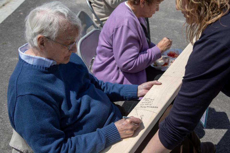 University of Kentucky professor and writer Gurney Norman signs a piece of wood during a wall raising event where nonprofit Housing Development Alliance announced it is constructing a 15-home subdivision in the Allais area of Hazard, Ky., Tuesday, May 11, 2021.