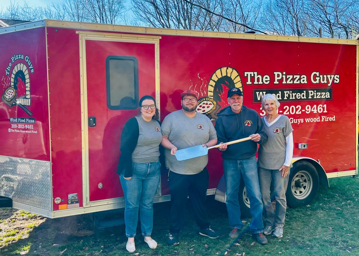 From right, former owners The Pizza Guys Cathy and Dave Wildenradt "pass the peel" to new owners Cody and MaryBeth Stewart.