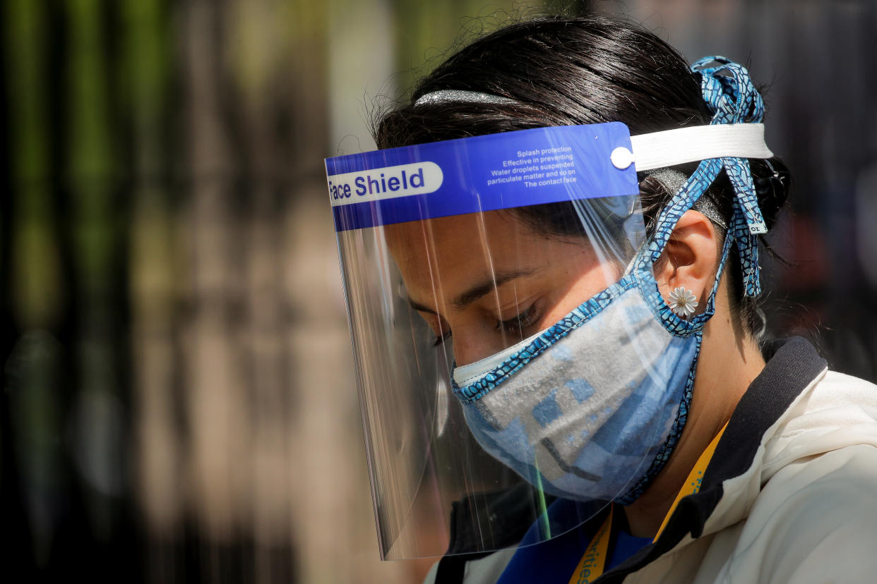 A volunteer wears a protective mask and face shield outside of a food bank at St. Bartholomew Church, during the outbreak of the coronavirus disease (COVID-19) in the Elmhurst section of Queens, New York City, New York U.S., May 15, 2020. REUTERS/Brendan McDermid