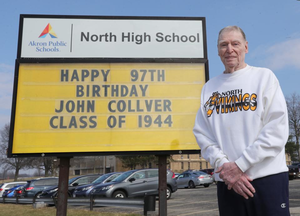 North High School graduate John Collver stands in front of a message board wishing him a happy 97th birthday.
