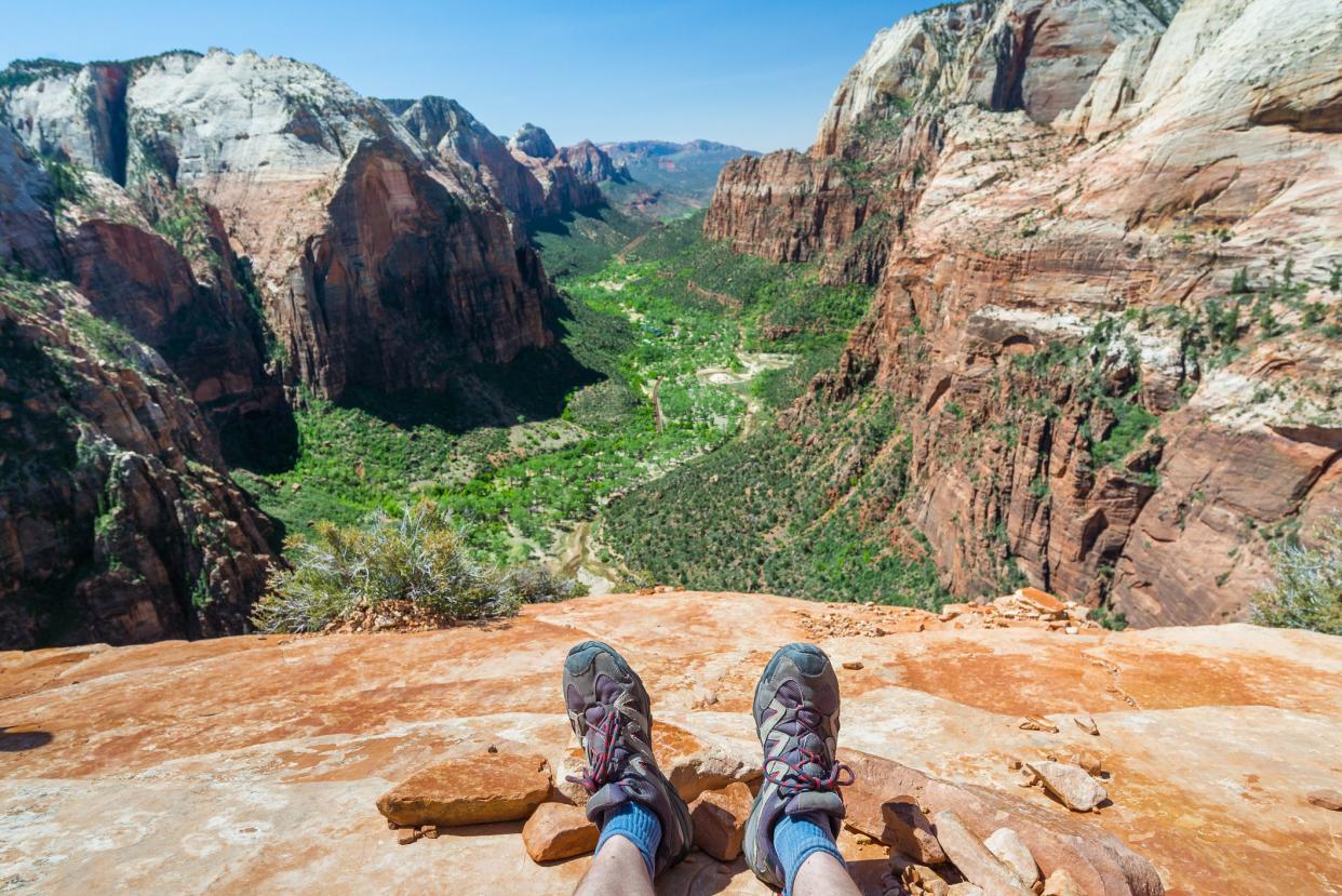 Feet of hiker relaxing on top of the mountain, travel background, hiking shoes at Angel's landing in Zion National Park, Usa.