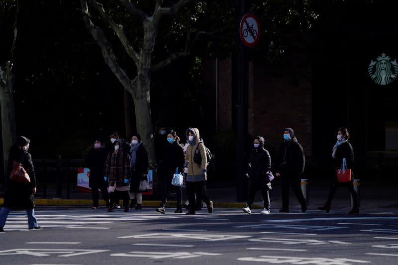 Pedestrians wearing face masks cross a road, as the country is hit by an outbreak of the novel coronavirus, in Shanghai
