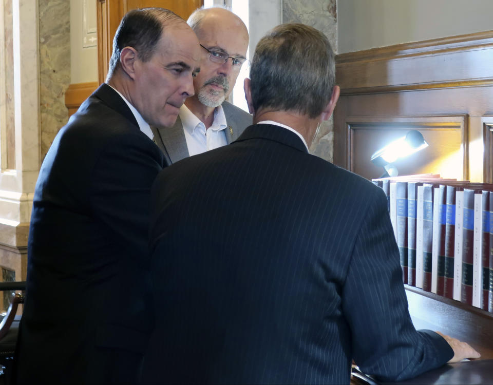 Kansas state Rep. Steven Johnson, left, R-Assaria, confers with Rep. Les Mason, center, R-McPherson, and Rep. Jim Gartner, D-Topeka, while the House debates school funding legislation, Thursday, April 4, 2019, at the Statehouse in Topeka, Kansas. Lawmakers are not sure that Democratic Gov. Laura Kelly's proposal to increase education funding by roughly $90 million a year would satisfy a Kansas Supreme Court mandate. (AP Photo/John Hanna)