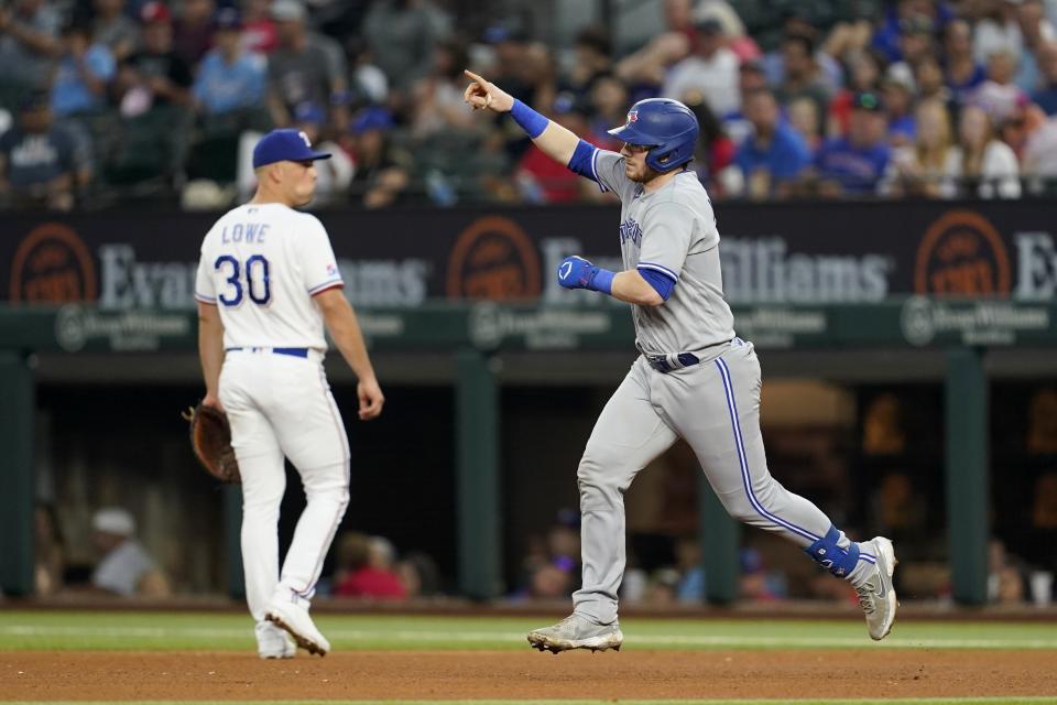 Toronto Blue Jays' Danny Jansen, right, celebrates his two-run home run as he runs past Texas Rangers first baseman Nathaniel Lowe (30) in the fourth inning of baseball game in Arlington, Texas, Saturday, Sept. 10, 2022. Cavan Biggio also scored on the hit. (AP Photo/Tony Gutierrez)