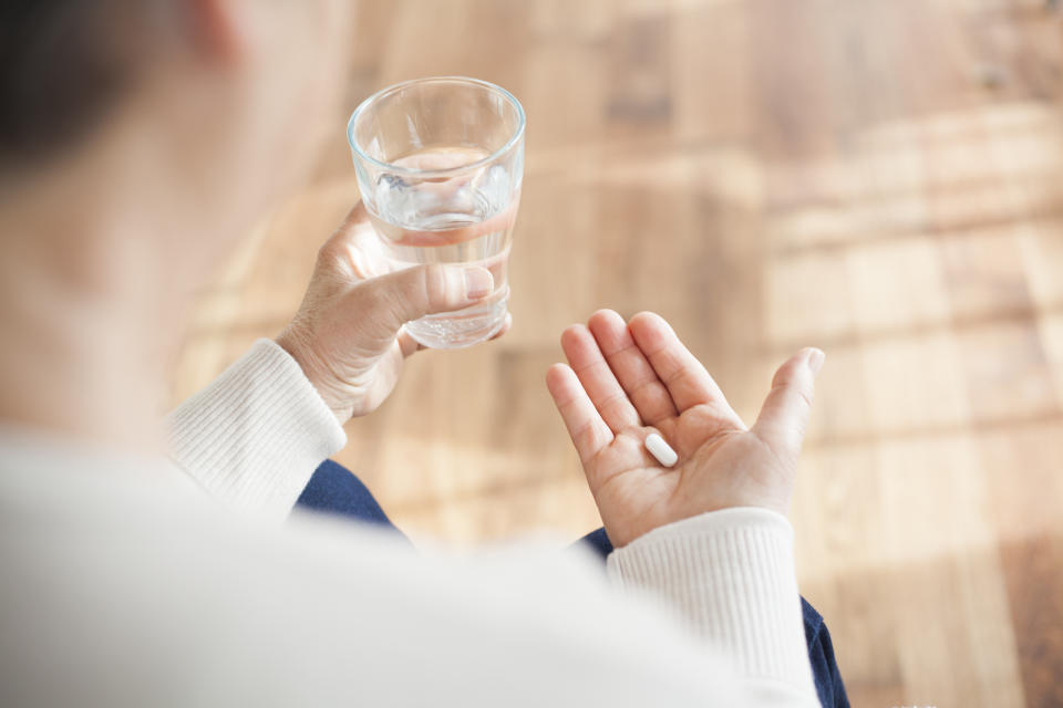 close-up of sick senior woman sitting on chair taking pills