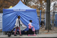 Pedestrians pass testing tent at a COVID-19 mobile testing site outside of a playground, Wednesday, Nov. 11, 2020, in the Brooklyn borough of New York. Restaurants, bars and gyms will have to close at 10 p.m. across New York state in the latest effort to curb the spread of the coronavirus, Gov. Andrew Cuomo announced Wednesday. Cuomo said the new restrictions, which go into effect Friday, are necessary because new coronavirus infections have been traced to those types of activities. (AP Photo/John Minchillo)