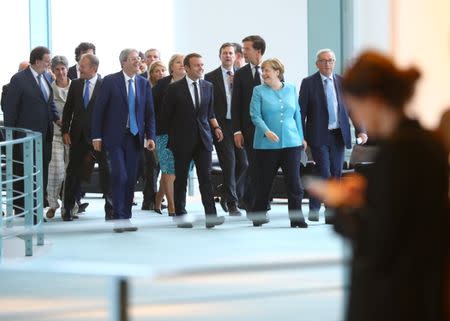 French President Emmanuel Macron and German Chancellor Angela Merkel on their way to the press conference after the meeting at the Chancellery in Berlin, Germany June 29, 2017. REUTERS/Hannibal Hanschke