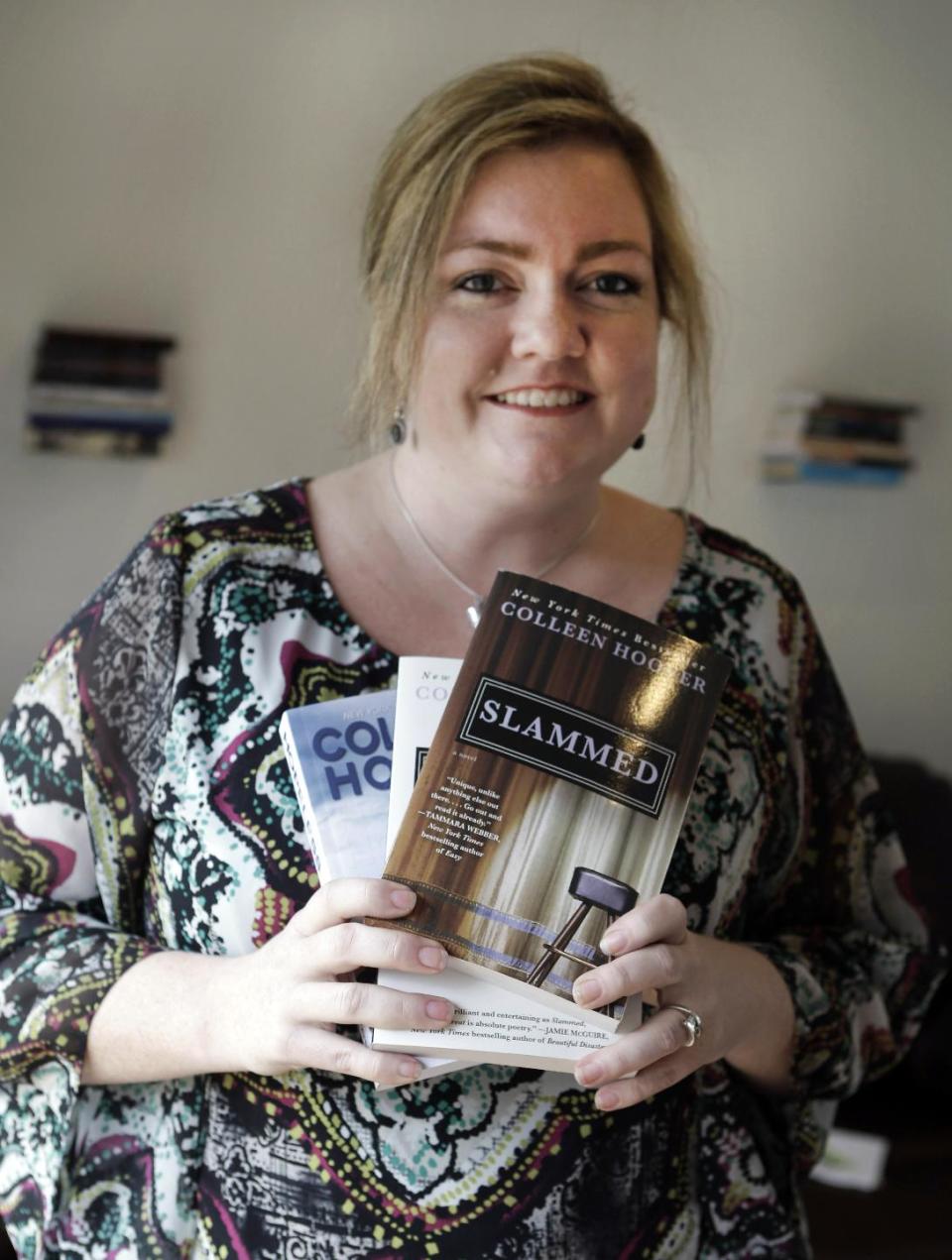In the photo made Tuesday, Feb. 5, 2013, self publishing author Colleen Hoover posses and holds copies her books in Sulphur Springs, Texas. Hoover's romance novels books have made the New York Times bestseller list. (AP Photo/LM Otero)