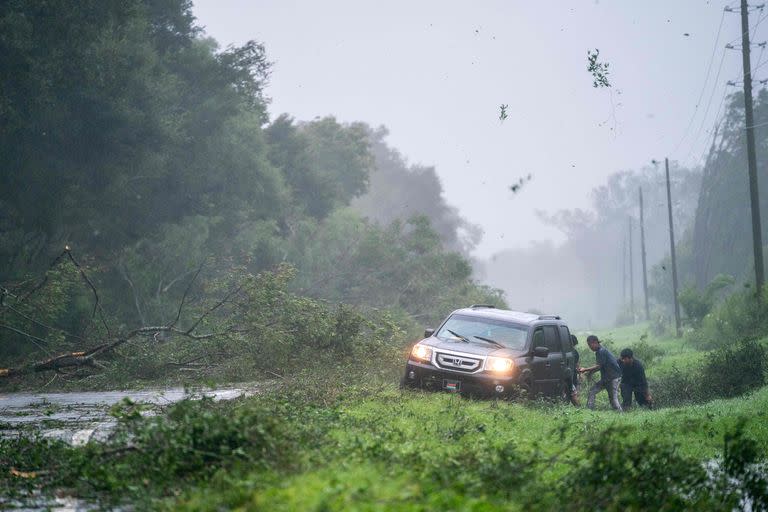 La gente trabaja para liberar un vehículo atrapado en la tormenta mientras el huracán Idalia cruza el estado el 30 de agosto de 2023 cerca de Mayo, Florida