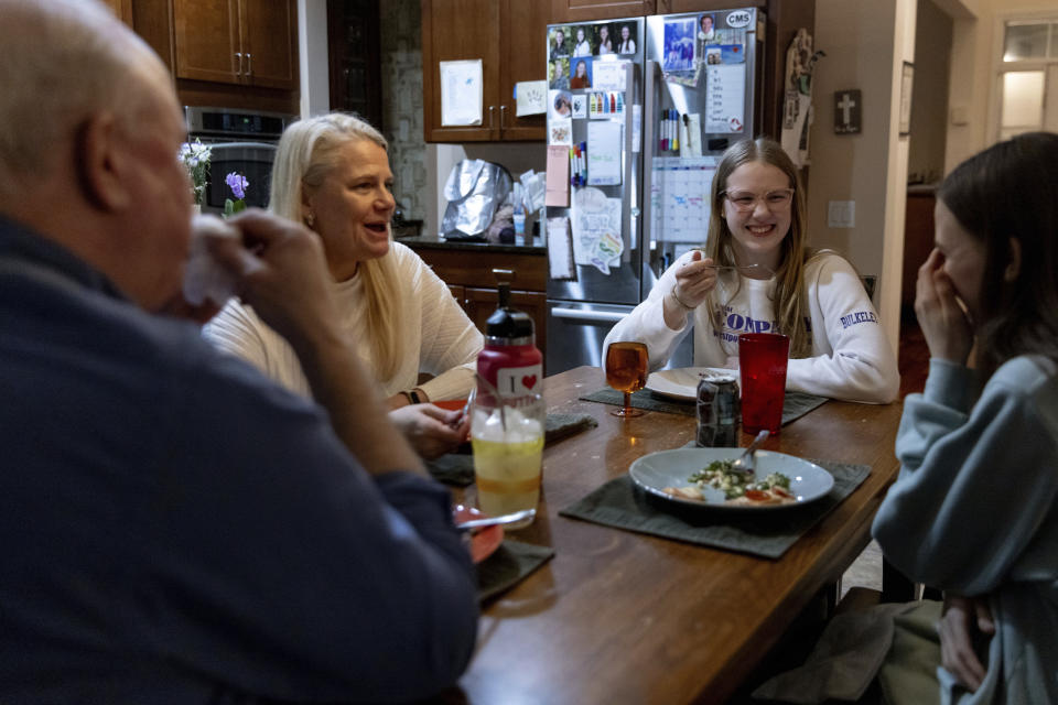 Kate Bulkeley, second from right, eats dinner with her family, Friday, Feb. 16, 2024, in Westport, Conn. With the damaging consequences of social media increasingly well documented, many parents are trying to raise their children with restrictions or blanket bans. Teenagers themselves are aware that too much social media is bad for them, and some are initiating social media “cleanses” because of the toll it takes on mental health and grades. (AP Photo/Julia Nikhinson)