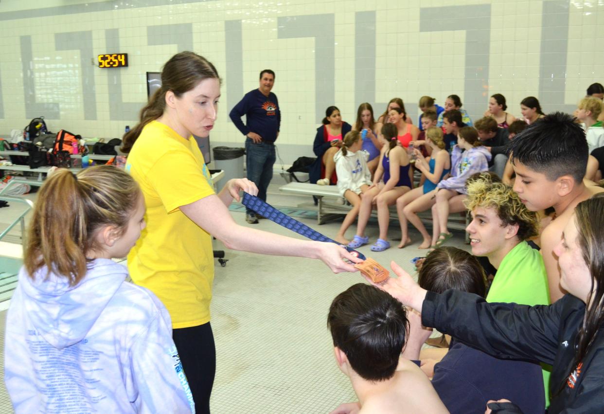 Miranda Tucker, a former University of Michigan swim standout, Big Ten champion and Olympic Trials qualifier, shows off one of her Big Ten medals to youth swimmers at the Sunshine Toyota Stroke Clinic at Lakeview High School on Saturday.