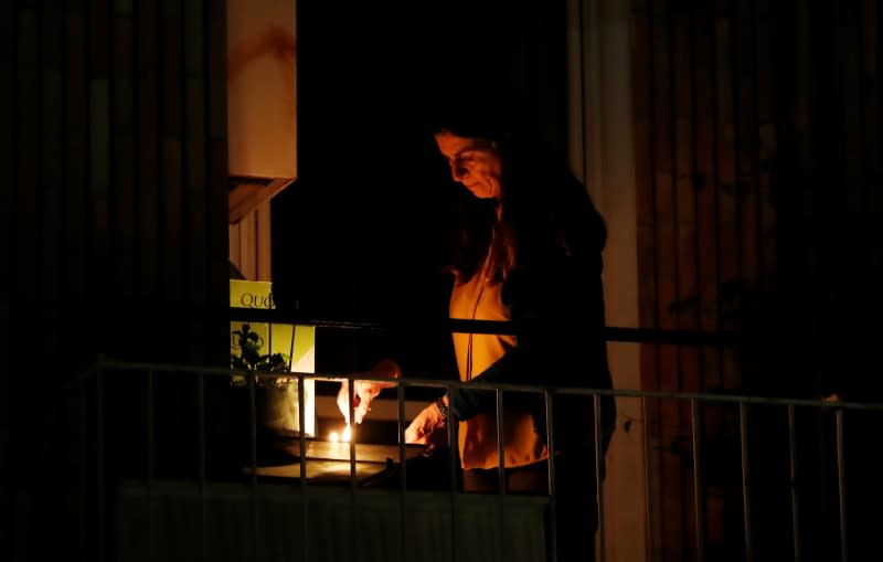 A woman lights a candle on her balcony as faithful across Italy say a prayer for people suffering from coronavirus disease (COVID-19)