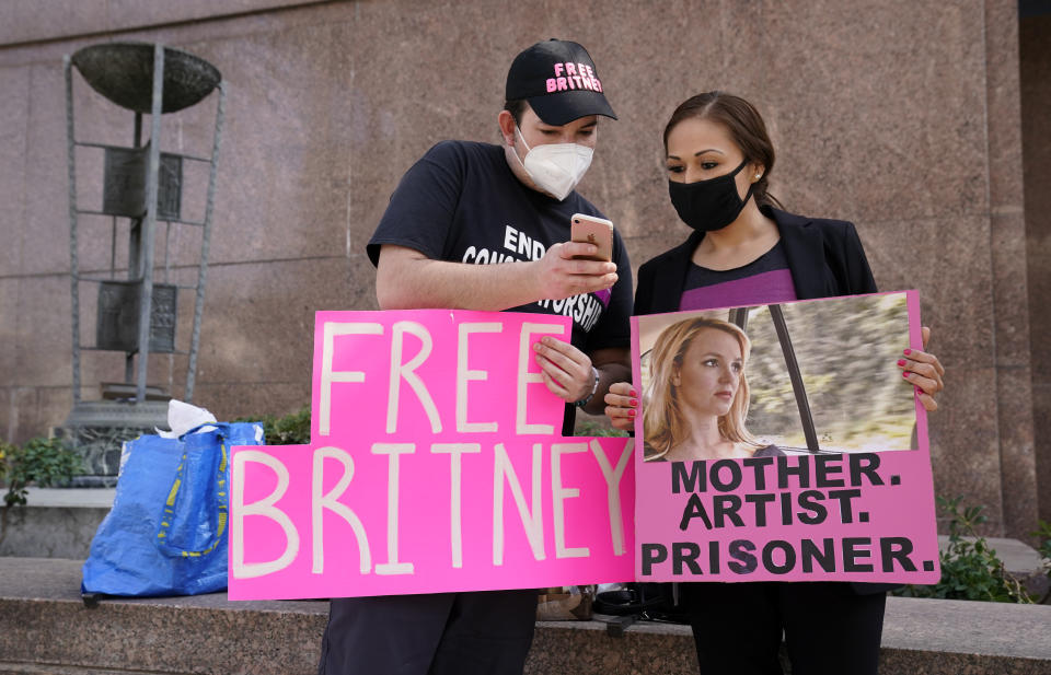 Britney Spears supporters Dustin Strand, left, and Kiki Norberto, both of Phoenix, mingle outside a court hearing concerning the pop singer's conservatorship at the Stanley Mosk Courthouse, Thursday, Feb. 11, 2021, in Los Angeles. (AP Photo/Chris Pizzello)