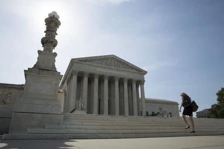 A woman walks to the Supreme Court in Washington June 19, 2014. REUTERS/Joshua Roberts