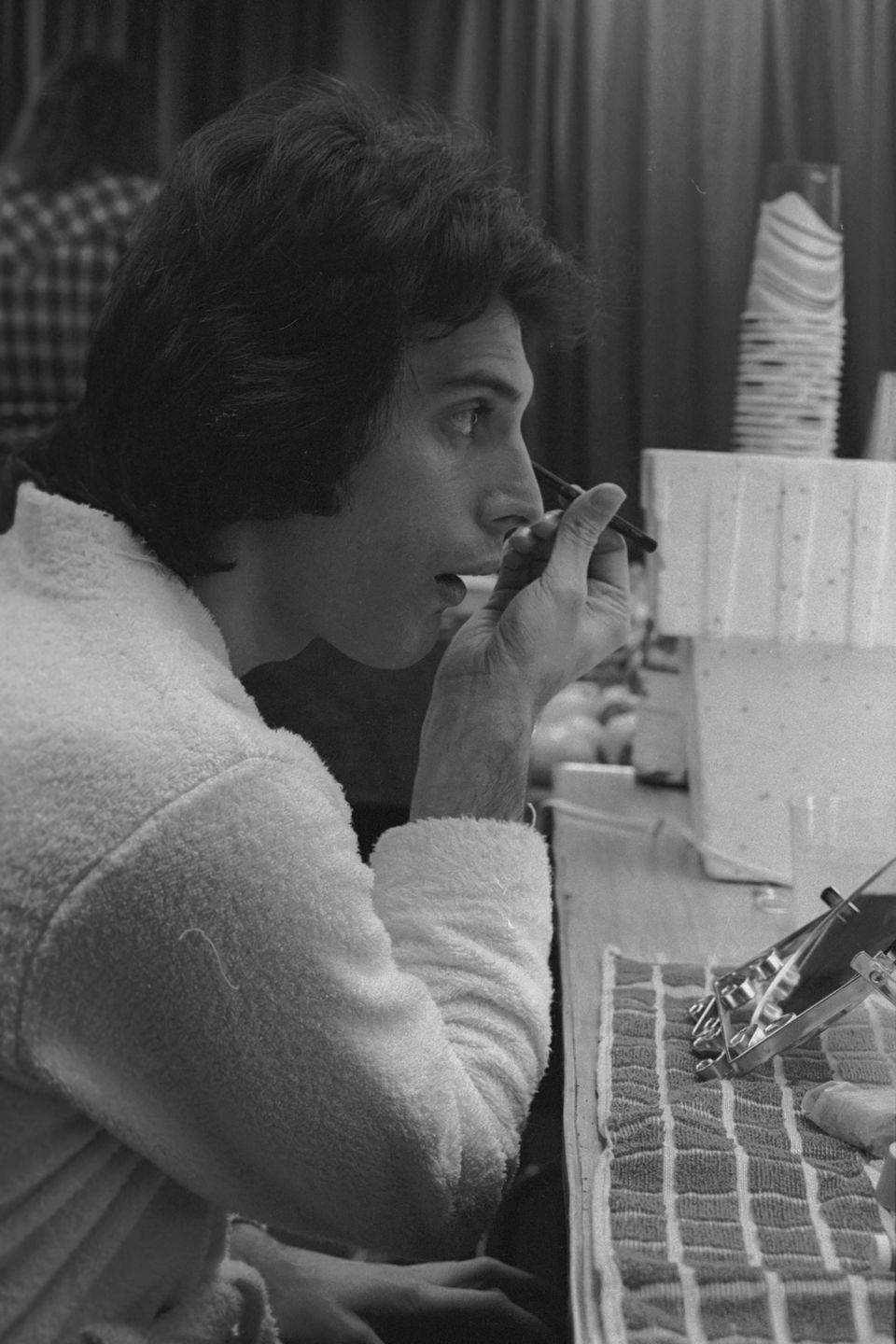 <p>Freddie Mercury of Queen applies make-up backstage before a concert in the US, January 1977.</p>