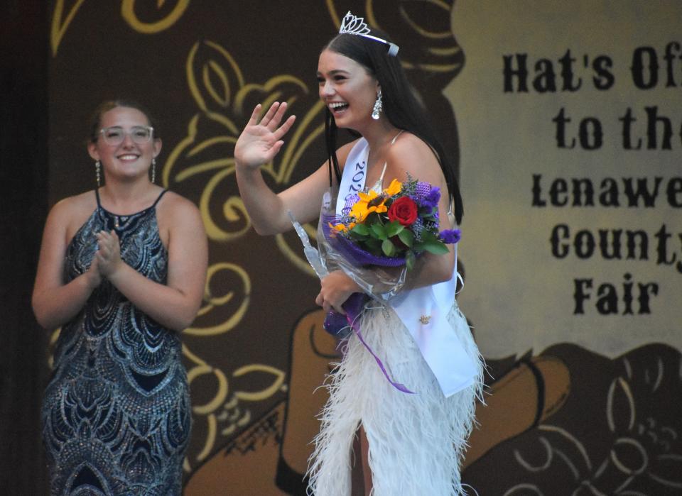 Emily Maran, the new Lenawee County fair queen for 2023, waves to the crowd after being crowned Sunday evening during opening day of the Lenawee County Fair. Pictured in the background is Riley Buckmaster, who also competed in Sunday's Queen's contest and earned the Miss Congeniality Award.