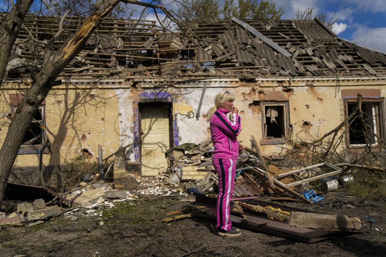 Iryna Martsyniuk, 50, stands next to her house, heavily damaged after a Russian bombing in Velyka Kostromka village, Ukraine, Thursday, May 19, 2022.