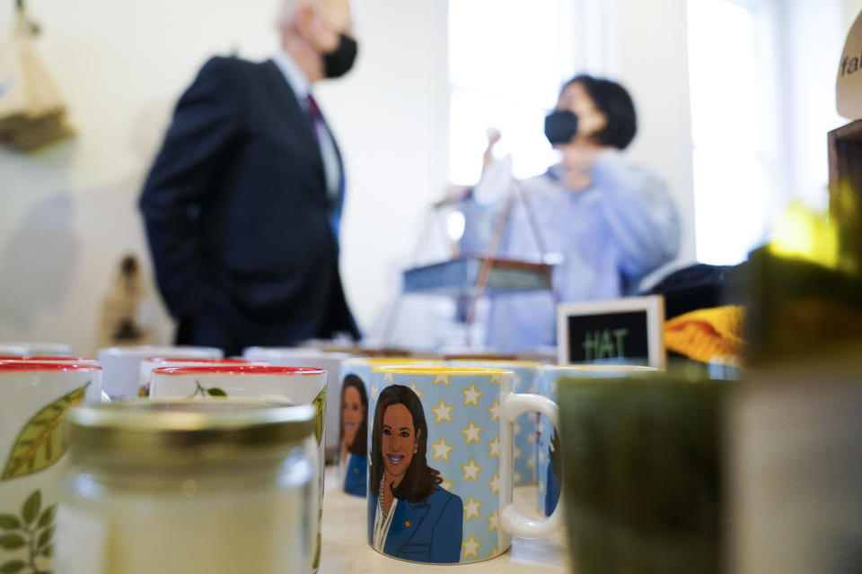 A mug with a depiction of Vice President Kamala Harris rests on a table as President Joe Biden talks with Honey Made store owner Viboonrattana 