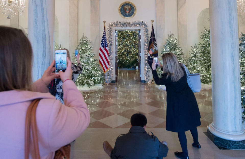People photograph Christmas trees during a preview of holiday decorations in the Grand Foyer of the White House in Washington,