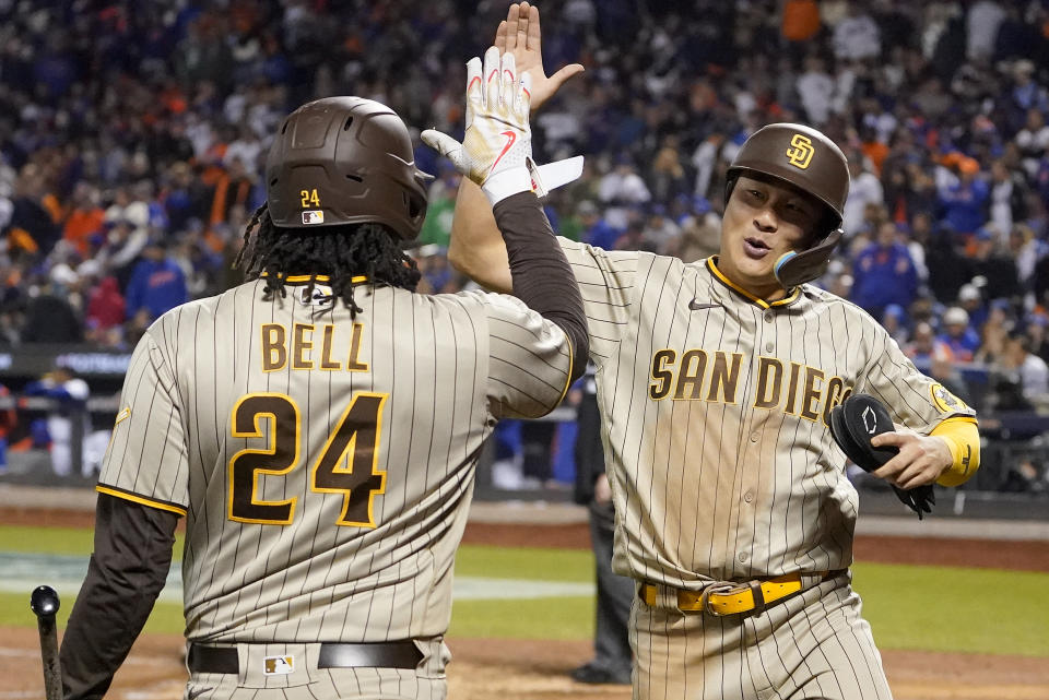 El campocorto Ha-Seong Kim, derecha, de los Padres de San Diego, festeja con el primera base Josh Bell (24) tras anotar carrera con un hit de Juan Soto ante los Mets de Nueva York en el octavo inning del tercer partido de la serie de comodines de la Liga Nacional, el domingo 9 de octubre de 2022, en Nueva York. (AP Foto/John Minchillo)