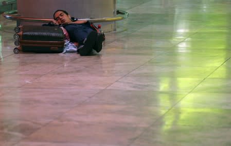 A stranded passenger sleeps on the floor of the arrivals hall at Alicante airport