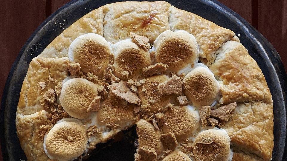 smores galette in a metal pie dish with toasted marshmallows and graham cracker pieces on top