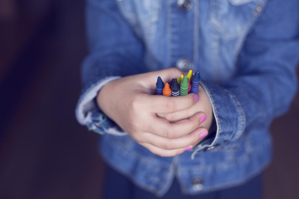 A child holds a bunch of crayons