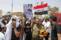 Supporters of the Shiite cleric Muqtada al-Sadr hold prayer near the parliament building in Baghdad, Iraq, Friday, Aug. 12, 2022. Al-Sadr's supporters continue their sit-in outside the parliament to demand early elections. The photo show Muqtada al-Sadr and his late father Muhammed Sadiq al-Sadr. (AP Photo/Anmar Khalil)