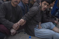 A man make massage to the hand of a competitor during wrestling matches in Kabul, Afghanistan, Friday, Dec. 3 , 2021. The scene is one played out each week after Friday prayers in the sprawling Chaman-e-Huzori park in downtown Kabul, where men, mainly from Afghanistan's northern provinces, gather to watch and to compete in pahlawani, a traditional form of wrestling. (AP Photo/ Petros Giannakouris)