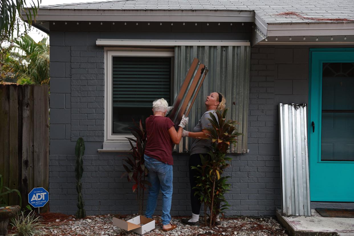 Rebecca Hale and her mother, Edda Howard, place shutters on her home as they prepare for the possible arrival of Hurricane Ian on Sept. 27, 2022, in St Petersburg, Fla. Ian is expected in the Tampa Bay area Wednesday night into early Thursday morning.