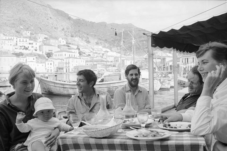 Norwegian expatriate Marianne Jensen (also known as Ihlen) (left) holds her son, Axel Jensen Jr, on her lap as friends watch, Hydra, Greece, October 1960. Leonard Cohen sits next to her. Source: Getty