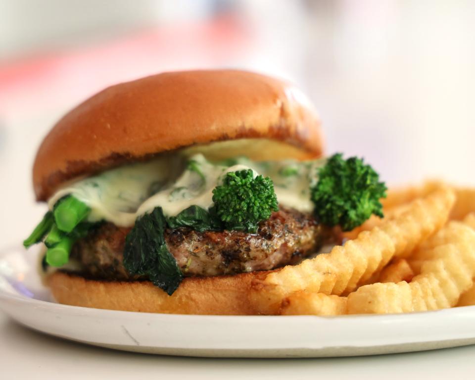 Tavern Pi's Italian Job burger stacks a ground pork patty, broccoli rabe and melted provolone on a brioche bun with basil vinaigrette. The restaurant is in Jupiter's Abacoa neighborhood.