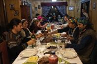 The Huenchupan family eats dinner during multiday celebrations of We Tripantu, the Mapuche new year, in Lof Soyinka, Los Rios, southern Chile, on Wednesday, June 22, 2022. (AP Photo/Rodrigo Abd)