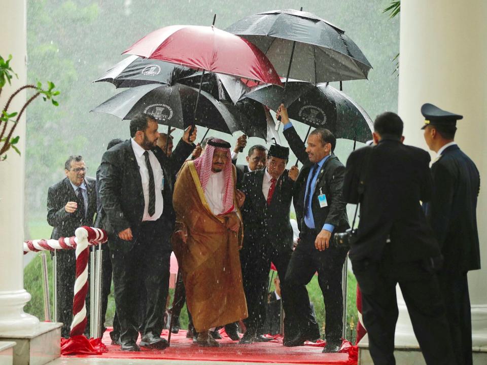 Saudi King Salman, center left, and Indonesian President Joko Widodo walk under umbrellas during heavy rain at the presidential palace in Bogor, West Java, Indonesia, Wednesday, March 1, 2017. Salman arrived in the world's largest Muslim nation on Wednesday as a part of a multi-nation tour aimed at boosting economic ties with Asia.