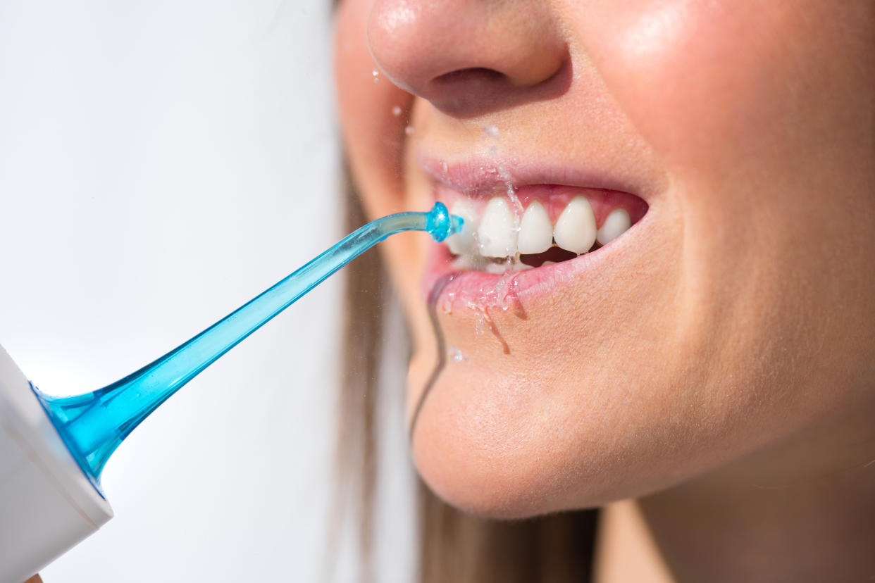 Close-up of a young woman using a water flosser