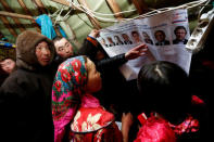 Members of the indigenous community "Yamb To" (Long Lake) look through a broadsheet with information about presidential candidates during the early voting in remote areas ahead of the presidential election, at a reindeer camping ground, about 450 km northeast of Naryan-Mar, in Nenets Autonomous District, Russia, March 1, 2018. REUTERS/Sergei Karpukhin