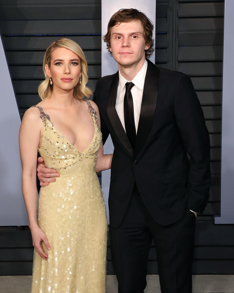 Emma Roberts in a sequined gown and Evan Peters in a black suit pose together at an event